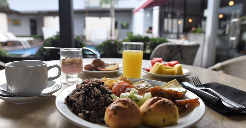 Picture of a meal being served in the dining room of the Costa Rica Medical Center Inn, San Jose, Costa Rica.  The picture shows a dinner meal served poolside with drinks.